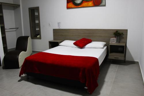 a bedroom with a bed with a red blanket and a chair at Hotel America 52 in Rionegro