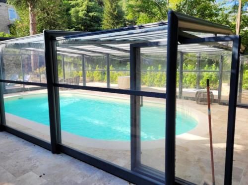 un poolhouse avec une baie vitrée et une piscine dans l'établissement Villa confortable à Carlux avec piscine privée et jardin, à Carlux