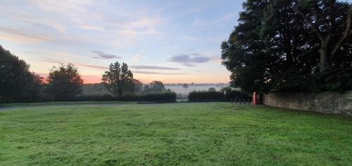 a large grass field with a sunset in the background at Ring O Bells Hinton Blewett in Bristol