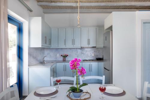 a kitchen with white cabinets and a table with pink flowers at Plori - Molos Apartments in Loutro