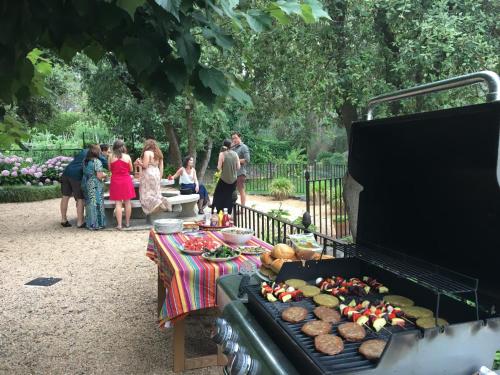 a group of people standing around a table with food on a grill at La Bruguera de Púbol Villa & Eco Retreat Centre in Púbol