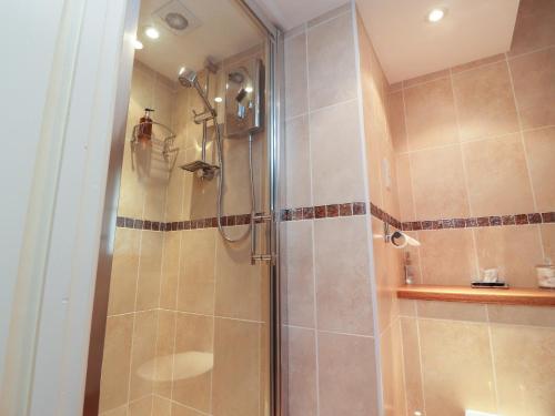 een douche met een glazen deur in een badkamer bij Coach House Cottage in Carnforth