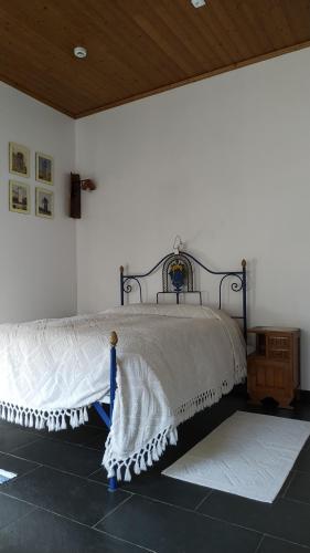 a bed in a room with a white wall at Casa do Lago in Vila de Rei