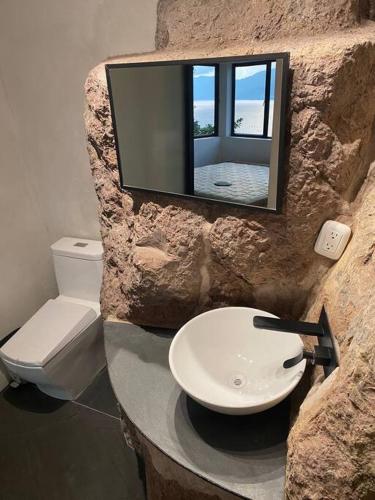 JaibalitoにあるRustic Charm Cliffside Retreatの石造りのバスルーム(洗面台、トイレ付)