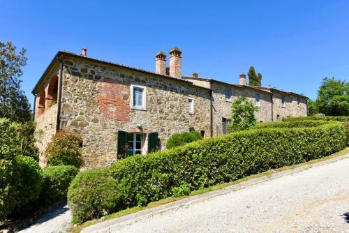 an old stone house with bushes in front of it at Piccolo Borgo Gagnoni in Sinalunga