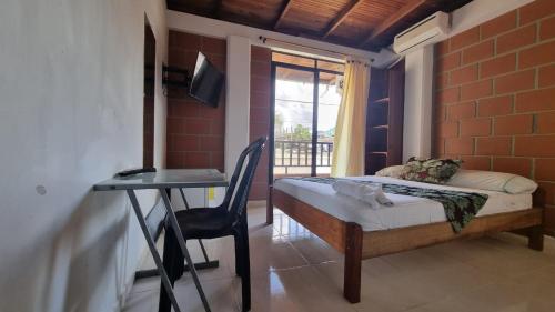 a bedroom with a bed and a desk and a window at Hotel Bahía Yubarta in Bahía Solano