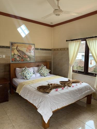 1 dormitorio con 2 camas y ventana en Tude's Family Homestay, en Ubud