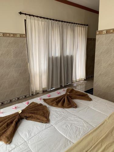 Una cama con dos mantas marrones encima. en Tude's Family Homestay, en Ubud