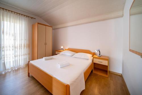 a bedroom with a large white bed and a window at Apartments Rajska Plaza (129) in Lopar