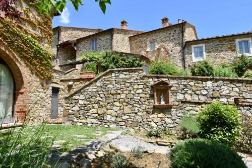 an old stone house with a stone wall at Piccolo Borgo Gagnoni in Sinalunga