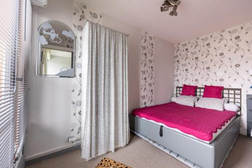 - une chambre dotée d'un lit avec des draps roses et un miroir dans l'établissement Le Pavillon - Appartement à 30 m de la plage, à Courseulles-sur-Mer