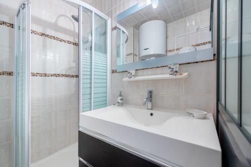 uma casa de banho com um lavatório e uma cabina de duche em vidro. em Le Pavillon - Appartement à 30 m de la plage em Courseulles-sur-Mer