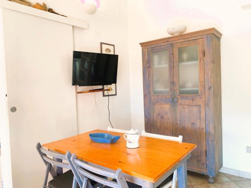 a dining room with a wooden table and a tv at La Vela Summer House - FREE WIFI - 700mt from the beach in Costa Rei
