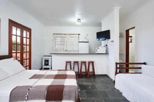a bedroom with two beds and a kitchen with a counter at Chalés Mirante da Lagoinha in Ubatuba