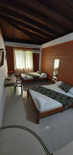 a room with three beds and a brick wall at Hotel Bahía Yubarta in Bahía Solano
