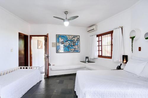 a white bedroom with two beds and a window at Chalés Mirante da Lagoinha in Ubatuba
