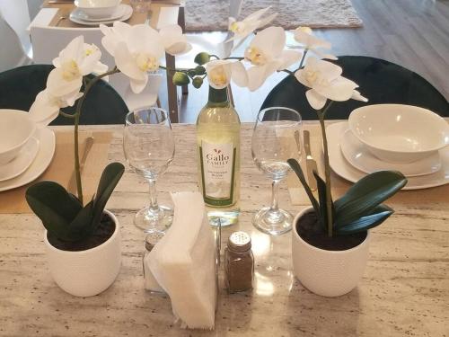 a table with a bottle of wine and glasses and flowers at Book Cozy King Bed Now 25 Percent OFF Spring Special! in Carteret