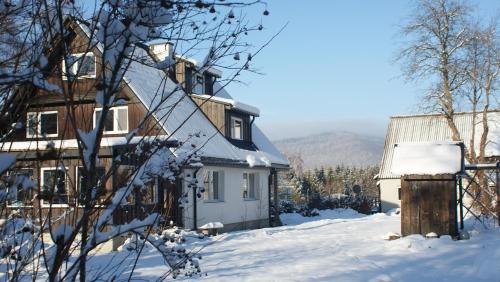 una casa con nieve en el suelo delante de ella en Podołynia, en Dwernik