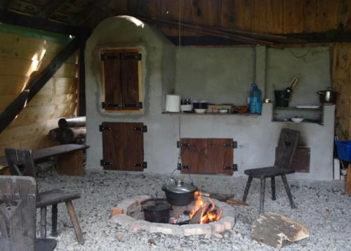 a kitchen with a stove with a pot and a fire at Podołynia in Dwernik
