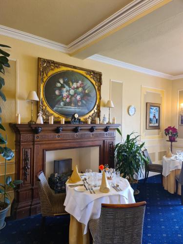 a dining room with two tables and a fireplace at Balcary Bay Country House Hotel in Auchencairn