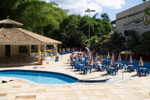a pool with chairs and umbrellas next to a building at Golden Dolphin Grand Hotel in Caldas Novas