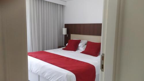 a bedroom with a large bed with red pillows at Dpto de 1 dormitorio, 402 Dos Orillas, Colonia in Colonia del Sacramento