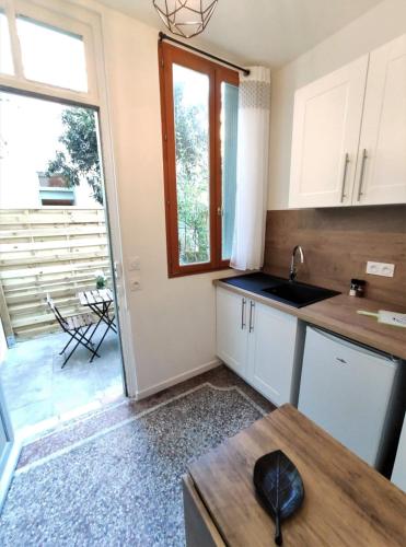 une cuisine avec un évier, une fenêtre et une table dans l'établissement LE CLOS DE BORIOS - ENTRE GARE ET HYPERCENTRE - TERRASSE, à Toulouse