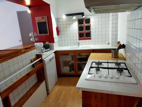 Il comprend une cuisine équipée d'une cuisinière et d'un comptoir blanc. dans l'établissement Agréable appartement de 48 m² en RDC, à La Bourboule