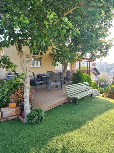 a wooden deck with a table and chairs under a tree at la noach in Metulla