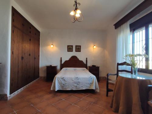 コニル・デ・ラ・フロンテーラにあるCasa Antoniaのベッドルーム1室(ベッド1台、テーブル、シャンデリア付)