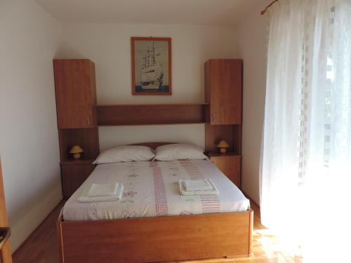 a bedroom with a bed with a wooden headboard at Apartmani Antica in Cres