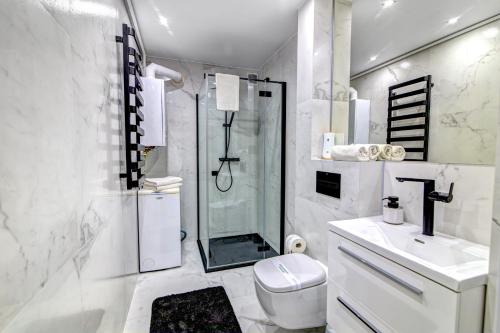 a white bathroom with a shower and a toilet at Krynica Apartamenty Apartament z sypialnią Centrum 105 Parking in Krynica Zdrój
