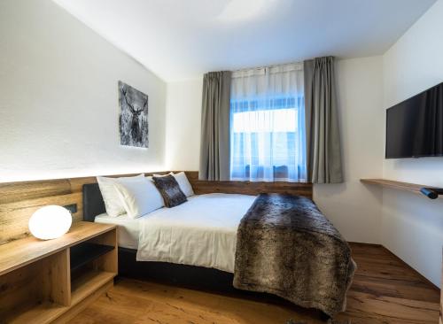 Habitación de hotel con cama y TV en Apartments Rainer - Val Gardena en Ortisei