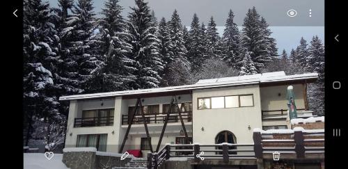 a building with snow covered trees in the background at Timis Valley, Casa Eni&Dan in Predeal