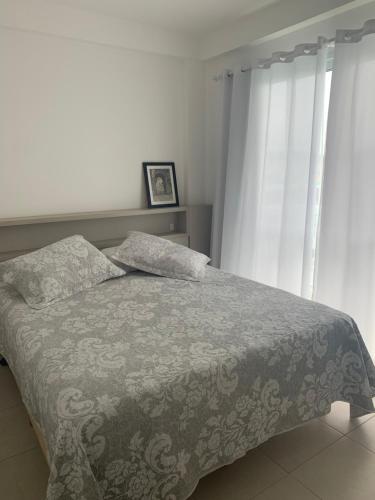 1 dormitorio con 1 cama con manta y cortinas en Apartamento em Home Club, en Penha