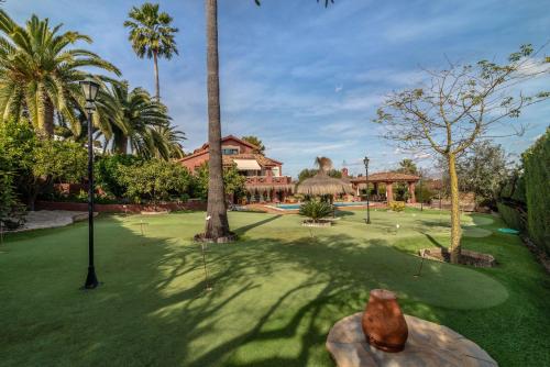 a golf course with palm trees and a house at Villa Olivar - 5 BDR Dream Pool/Jacuzzi/Golf/BBQ in Torremolinos