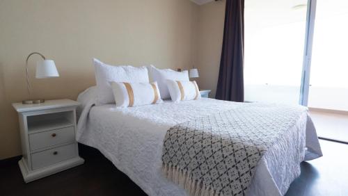 1 dormitorio con 1 cama blanca y mesita de noche en Departamento frente al mar Iquique, en Iquique