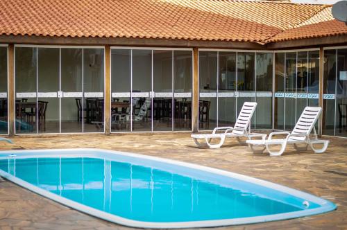 a swimming pool with two chairs and a table at Hotel Boituva Inn - Your Hotel in Boituva