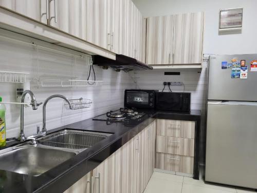 a kitchen with a sink and a refrigerator at HOMESTAY D'Univ 360 PLACE in Seri Kembangan