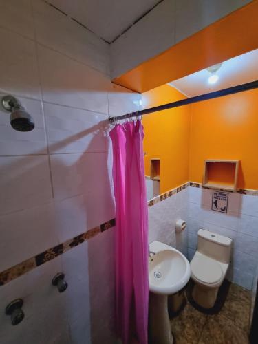 a bathroom with a pink shower curtain and a sink at Hostal refugio's in Ica