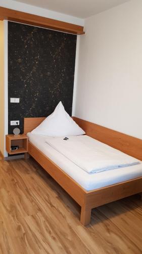 a bed in a bedroom with a wooden floor at Braustüble und Hotel zur Post in Weiler-Simmerberg