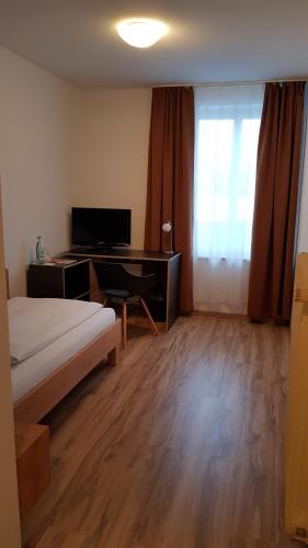 a bedroom with a bed and a desk with a computer at Braustüble und Hotel zur Post in Weiler-Simmerberg