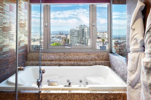 a bath tub in a bathroom with windows at Melia Madrid Princesa in Madrid