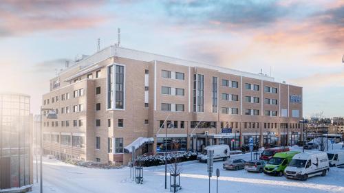 um grande edifício com carros estacionados num parque de estacionamento em Hotelli Sointu em Järvenpää
