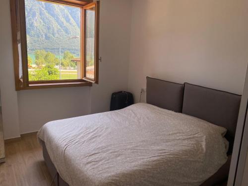 a bedroom with a white bed with a window at Casa Giulia - Appartamento Anfo in Anfo