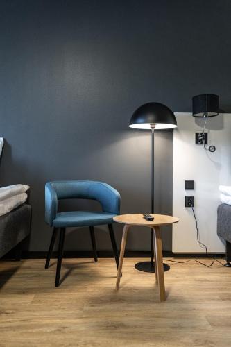 a room with a blue chair and a table at Hotelli Sointu by UHANDA in Järvenpää