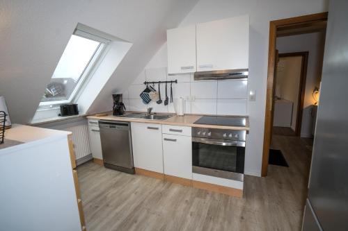 uma cozinha com armários brancos, um lavatório e uma janela em Kleines Juwel in Brunsbüttel em Brunsbüttel