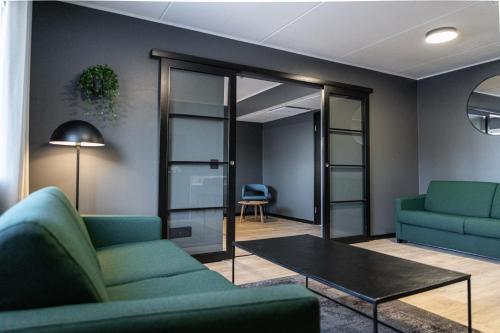 a living room with two green couches and a table at Hotelli Sointu by UHANDA in Järvenpää