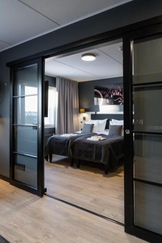 a bedroom with a bed and a sliding glass door at Hotelli Sointu by UHANDA in Järvenpää