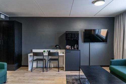 a living room with a table and a kitchen at Hotelli Sointu by UHANDA in Järvenpää
